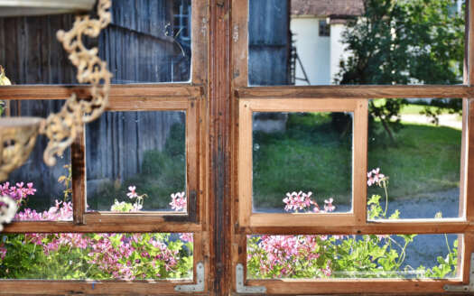 Holzfenster mit Blumen und Scheune – Frühjahrscheck Immobilie Senden